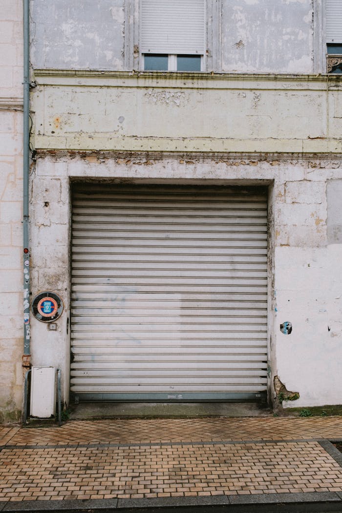 Services An old garage door with a weathered wall, showcasing urban decay and texture.