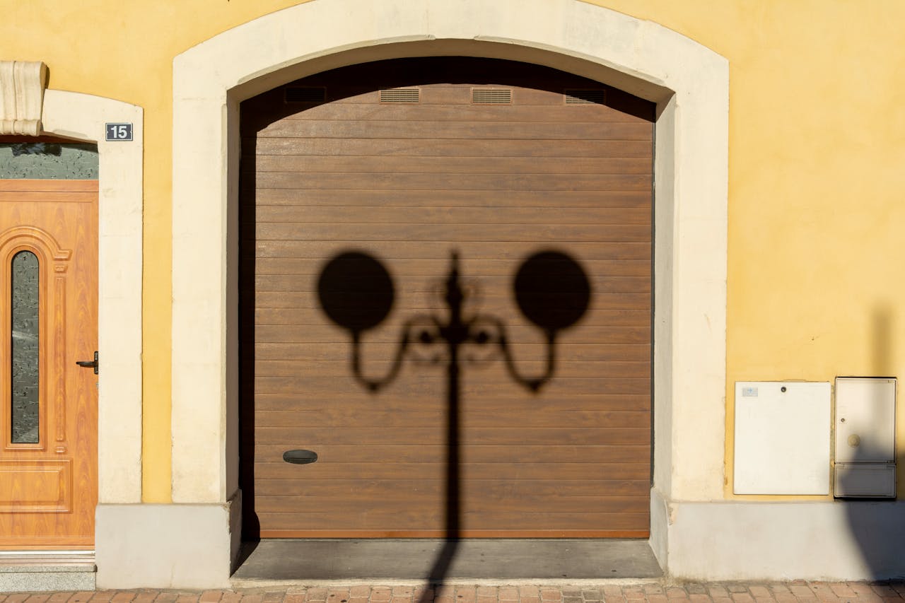 Services Wooden door and garage with streetlamp shadow on a sunny city street.