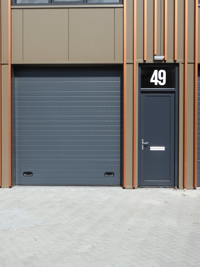 Services A contemporary building facade featuring a dark garage door and entrance with number 49.